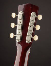 Close-up of a guitar headstock with tuning pegs on a dark background