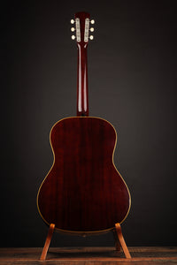 Acoustic guitar on a stand against a dark background
