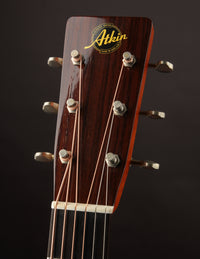 Close-up of a guitar headstock with Atkin logo on a dark background