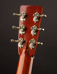 Close-up of a guitar headstock with tuning pegs on a dark background