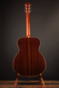 Acoustic guitar on a stand against a dark background