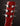 Close-up of a red guitar headstock with tuning pegs on a dark background