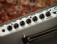 Guitar amplifier control panel with knobs and labels on a blurred background