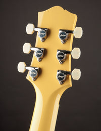 Close-up of a guitar headstock with tuning pegs on a dark background