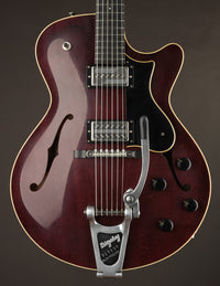 A Collings 620 model electric guitar with a glossy finish and Bigsby tremolo on a dark background