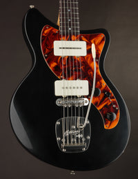 Black electric guitar with tortoiseshell pickguard on a dark background