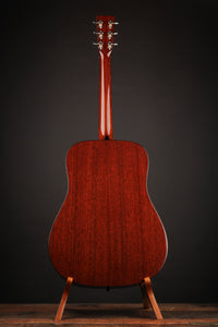 Back view of acoustic guitar on a stand against a black background