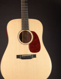 Acoustic guitar with a natural wood finish on a black background