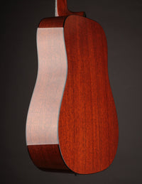 Acoustic guitar with a natural wood finish on a black background, back/side view