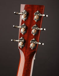 Close-up of a guitar headstock with tuning pegs on a dark background