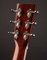 Close-up of a guitar headstock with tuning pegs on a dark background