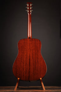 Acoustic guitar on a stand against a dark background