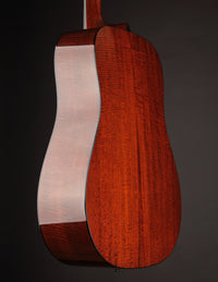 Acoustic guitar with a natural finish on a black background, back view