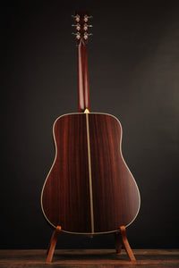 Collings acoustic guitar on a stand against a dark background (back)