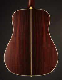 Back view of a Collings acoustic guitar on a dark background