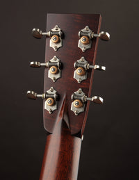 Close-up of a guitar headstock with tuning pegs on a dark background