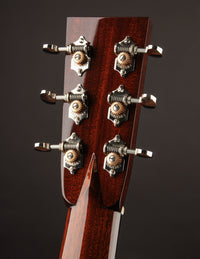 Close-up of a guitar headstock with tuning pegs on a dark background