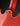 Close-up of a red guitar with a visible strap button on a dark background