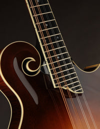Close-up of a mandolin's neck and scroll on a dark background