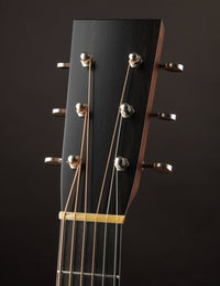 Close-up of a guitar headstock with tuning pegs on a dark background