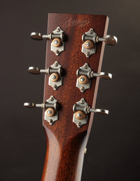 Close-up of a guitar headstock with tuning pegs on a dark background