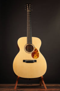 Acoustic guitar on a stand against a dark background