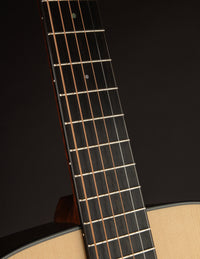 Close-up of a guitar neck with fretboard and strings against a dark background