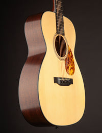 Side view of a Collings acoustic guitar with a natural finish on a black background.
