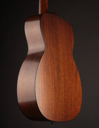 Side view of a Collings acoustic guitar with a natural finish on a black background.