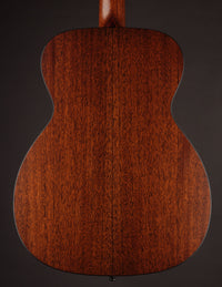 Back view of a Collings acoustic guitar on a black background.