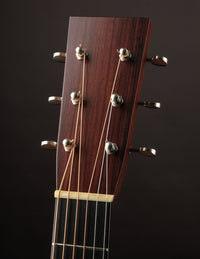 Close-up of a guitar headstock with tuning pegs on a dark background