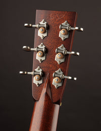 Close-up of a guitar headstock with tuning pegs on a dark background