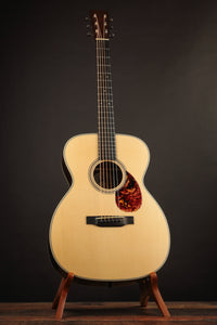 Acoustic guitar on a stand against a dark background