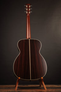 Acoustic guitar on a stand against a dark background