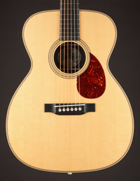 Acoustic guitar with a tortoiseshell pickguard on a black background
