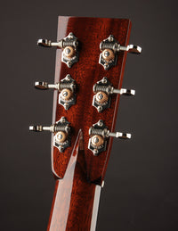 Close-up of a guitar headstock with tuning pegs on a dark background