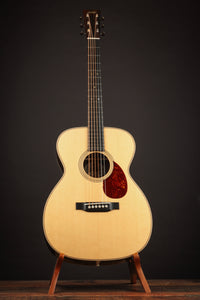 Acoustic guitar on a stand against a dark background
