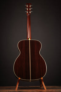 Acoustic guitar on a stand against a dark background