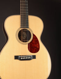 Acoustic guitar with a tortoiseshell pickguard on a black background