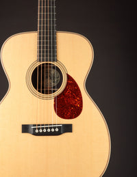 Acoustic guitar with a tortoiseshell pickguard on a black background