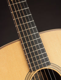 Close-up of a guitar's neck and soundhole with a dark background