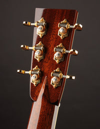 Close-up of a guitar headstock with tuning pegs on a dark background