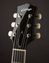Close-up of a Collings guitar headstock with tuning pegs on a dark background