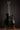 Black electric guitar on a stand against a dark background