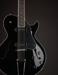 Black electric guitar on a black background