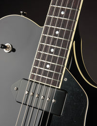 Close-up of a black electric guitar's neck on a dark background
