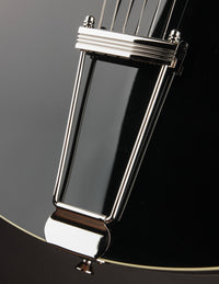 Close-up of a guitar's trapeze tailpiece on a black background