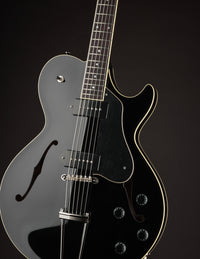 Black electric guitar on a black background