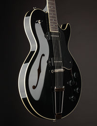 Black electric guitar on a dark background