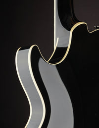 Close-up of a guitar's neck and cutaway on a black background